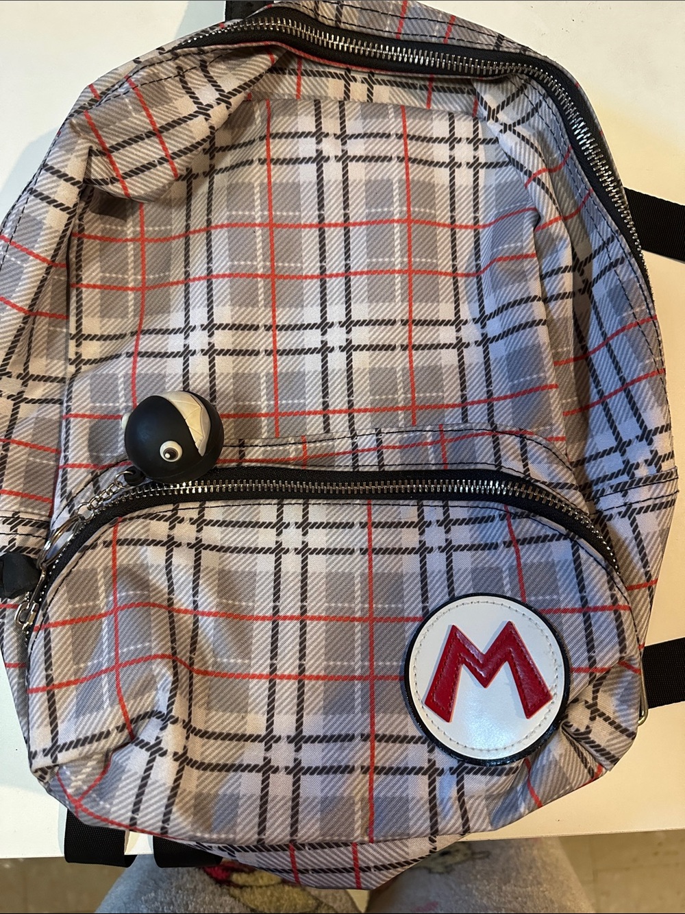 Gray Plaid Backpack with Red 'M' Accent
